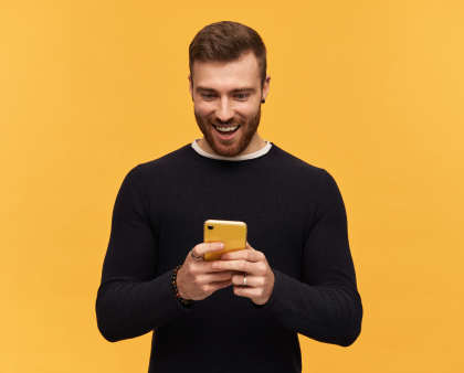 A man happily holds a phone, his face beaming with a smile