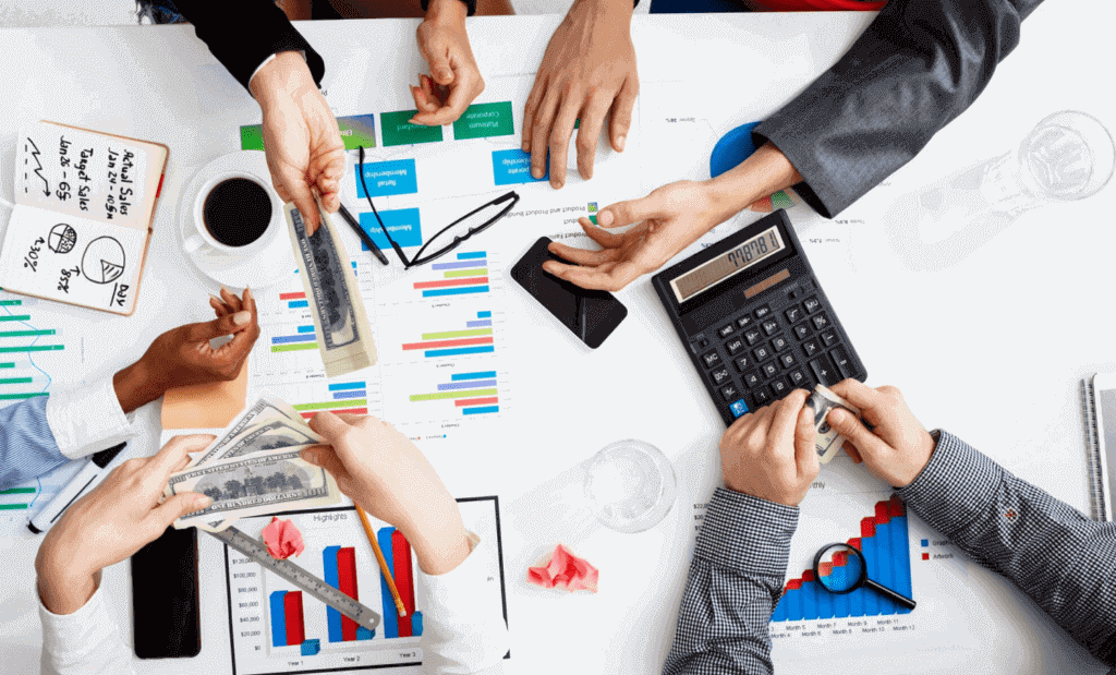 A group of professionals sitting around a table with money and documents, engaged in a business meeting