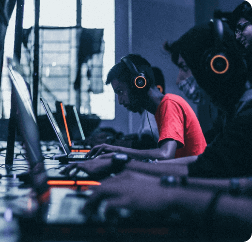 A group of people sitting at a table with laptops and wearing headphones